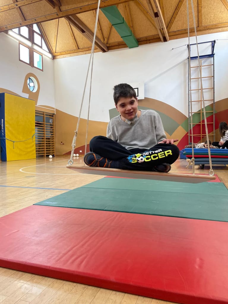 Kind schaukelt im Turnsaal über Matten