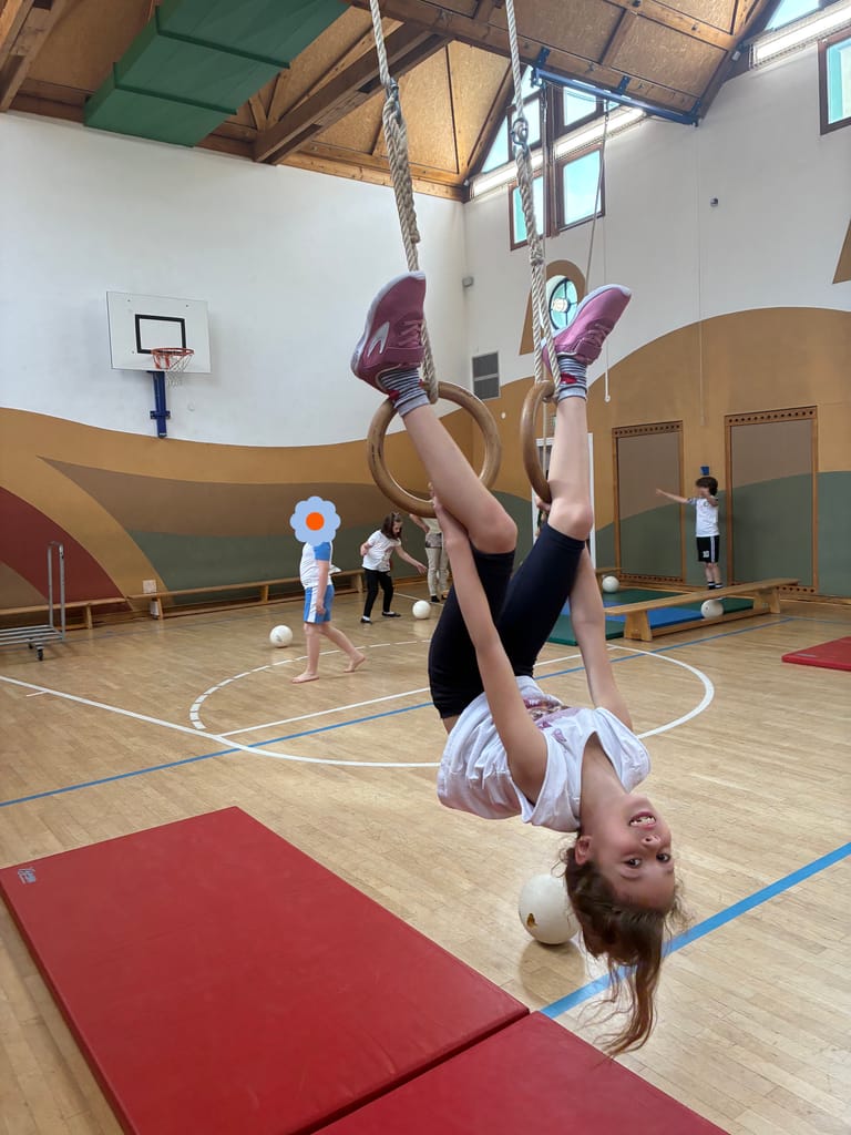 Kind turnt kopfüber auf den Ringen