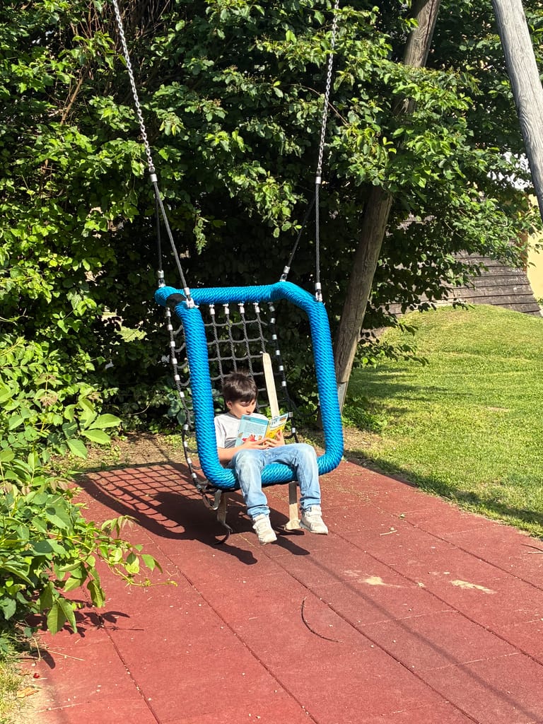 Kind liest in Korbschaukel