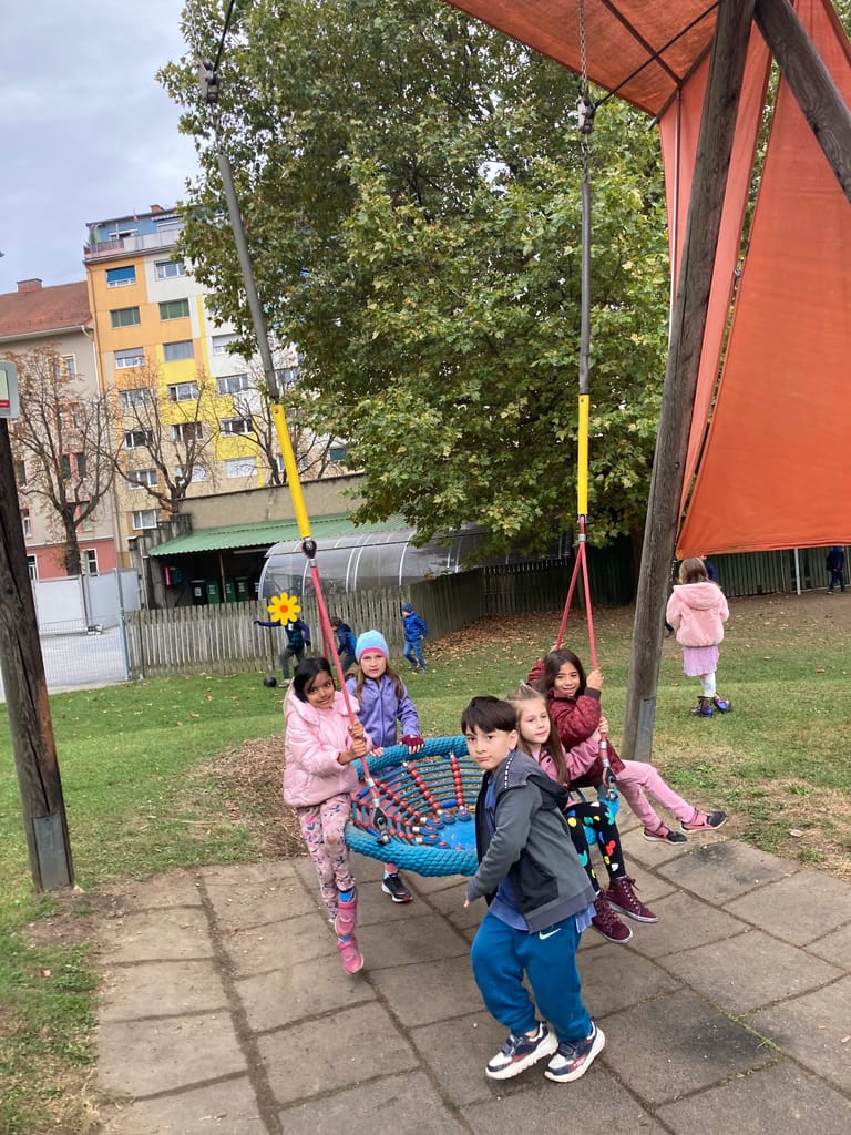 Kinder schaukeln in der Korbschaukel.