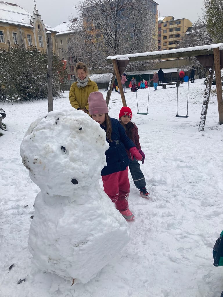 Kinder bauen einen riesigen Schneemann.