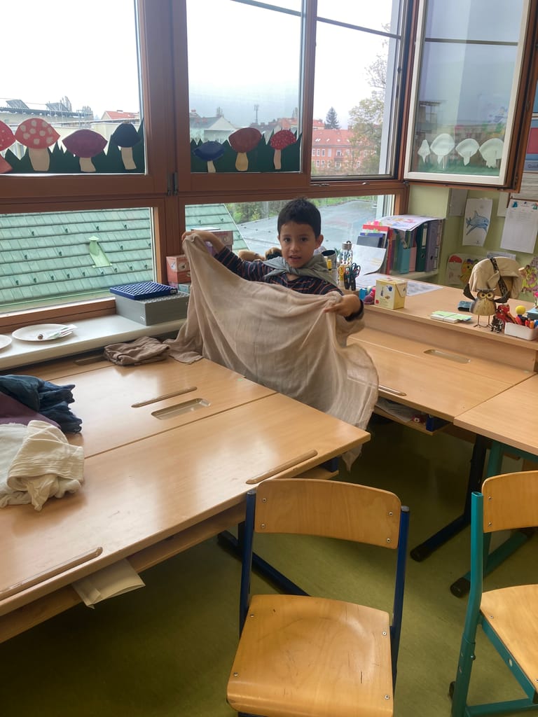 Kind baut sich mit Tuch einen Unterschlupf.