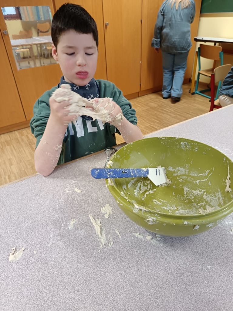 Kind formt aus Teig eine Kugel.