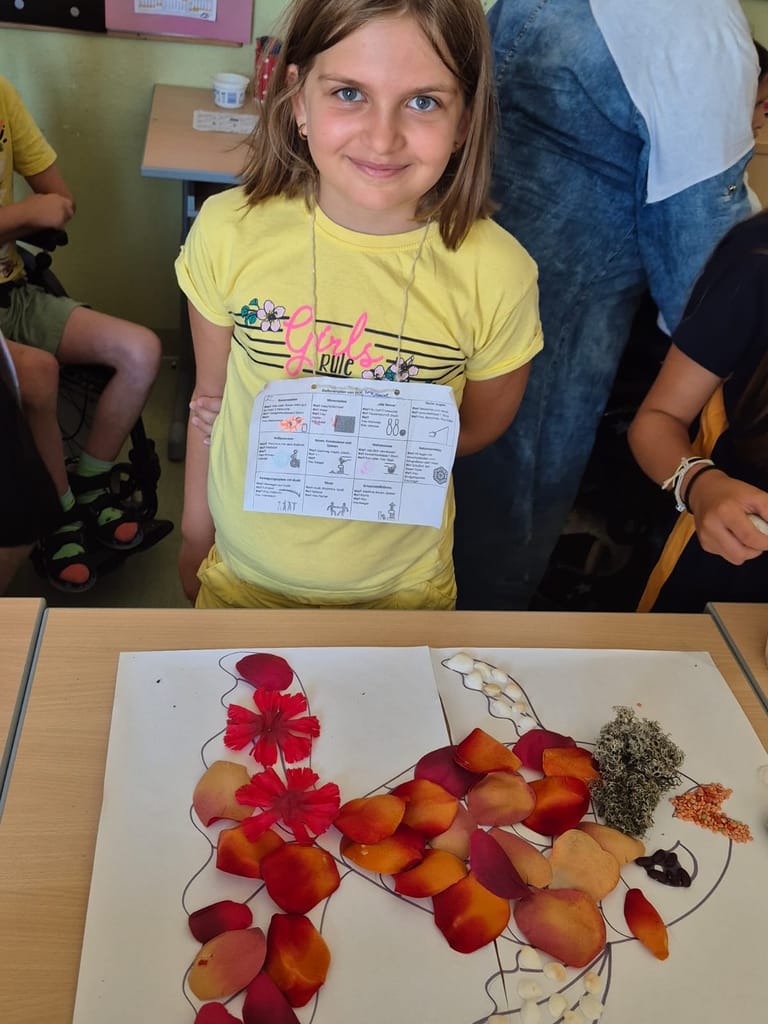 Mädchen steht vor Bild, das sie mit Naturmaterialien gelegt hat.