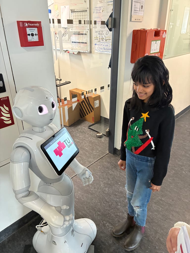 Kind steht vor Roboter und lacht.