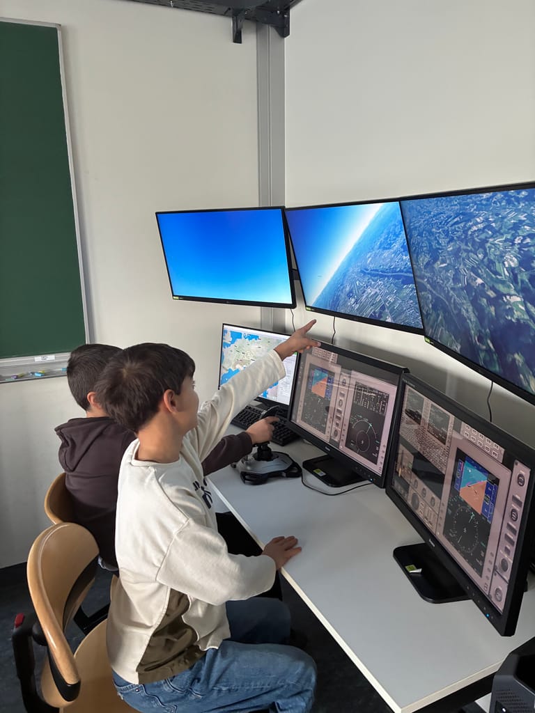 Zwei Kinder sitzen an einem Flugsimulator.