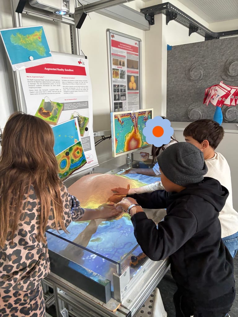 Kinder greifen in Sandkasten und bauen Berge.