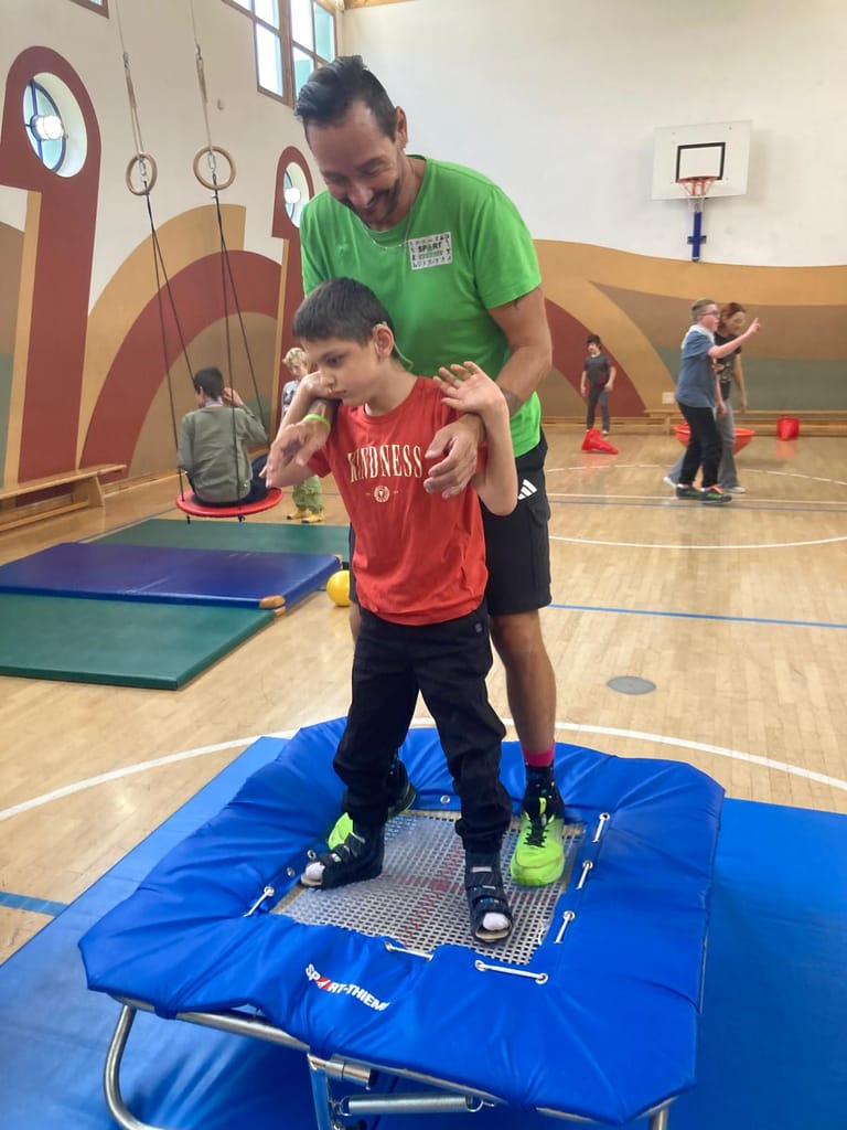 Trainer steht mit Bub auf einem Trampolin