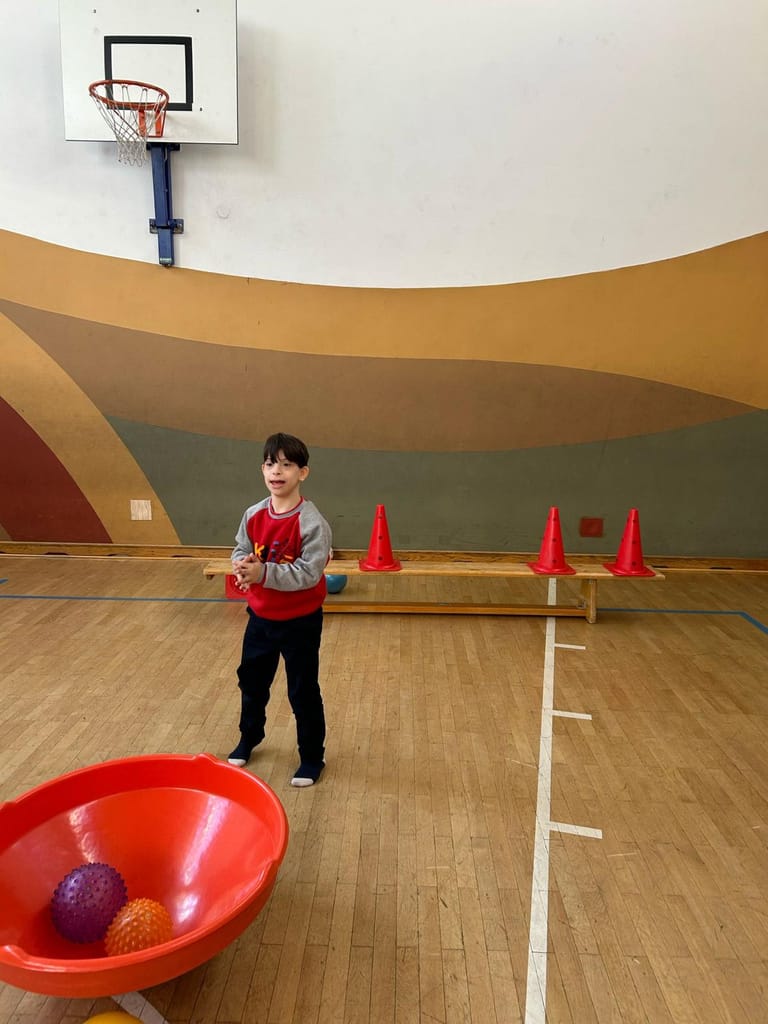 Kind wirft Bälle in einen Korb.