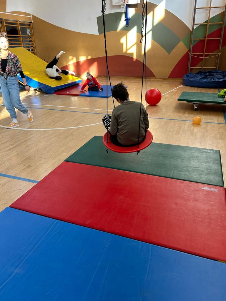 Ein Kind sitzt auf der Schaukel im Turnsaal.