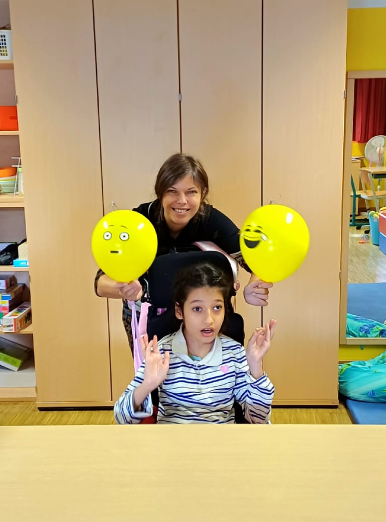 Kind hat zwei Luftballone - einen mit einem traurigen und einen mit einem fröhlichen Gesicht.