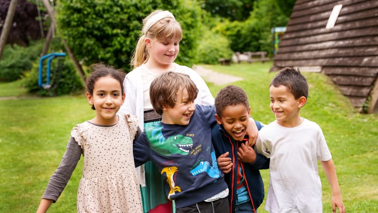 Fünf Kinder tollen miteinander und lachen