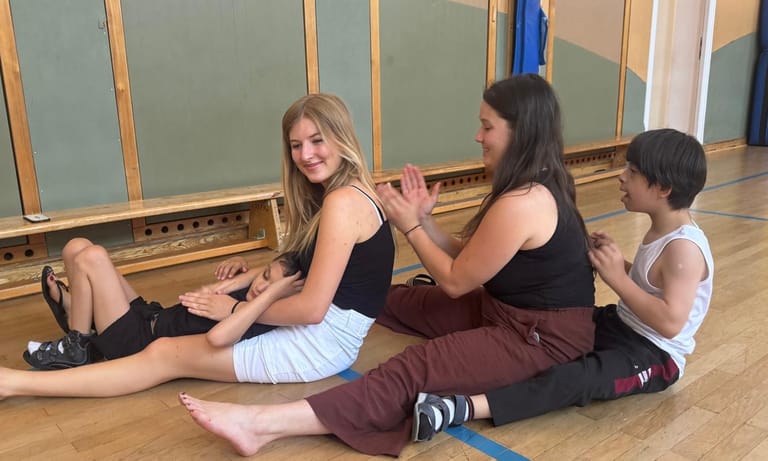 Vier Personen sitzen hintereinander und massieren sich den Rücken