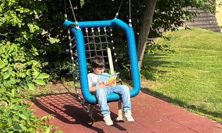 Kind liest in Korbschaukel