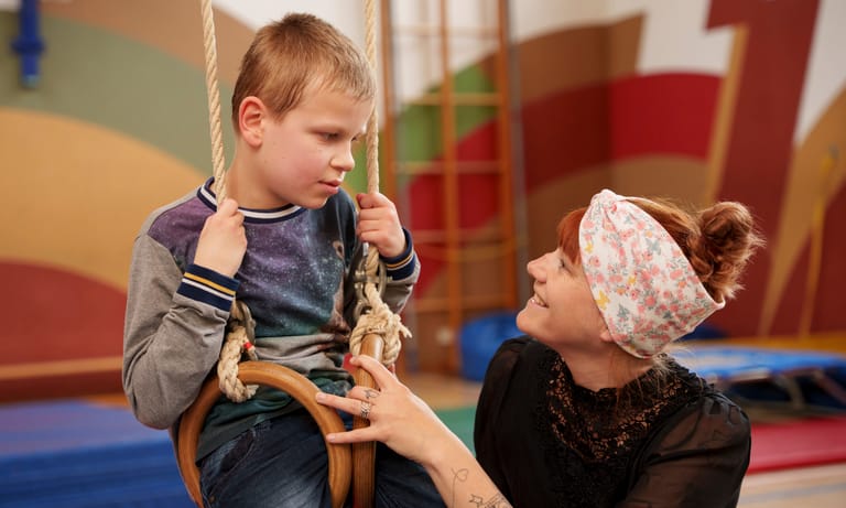 Kind sitzt in den Ringen und schaukelt