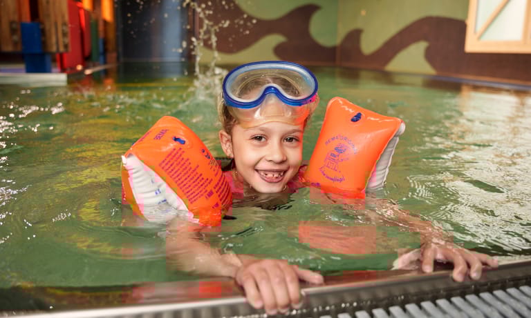 Kind schwimmt mit Schwimmflügeln im Becken