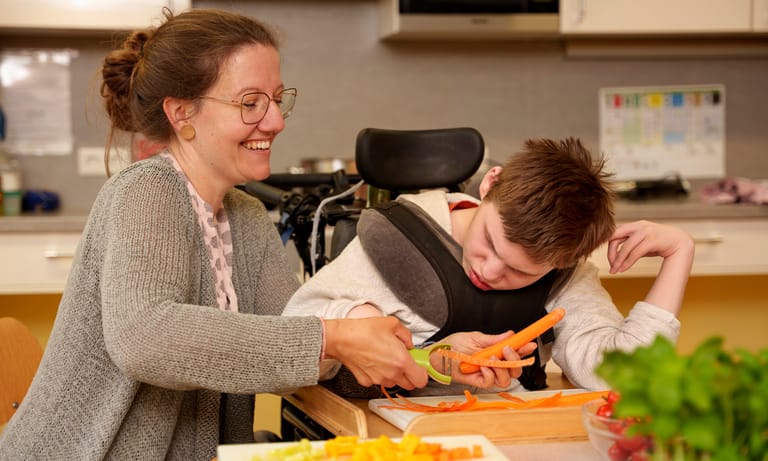 Lehrerin schneidet mit Kind zusammen Karotten