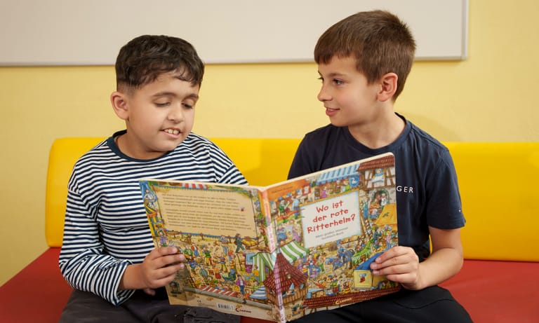 2 Kinder schauen sich ein Ritterbuch an.