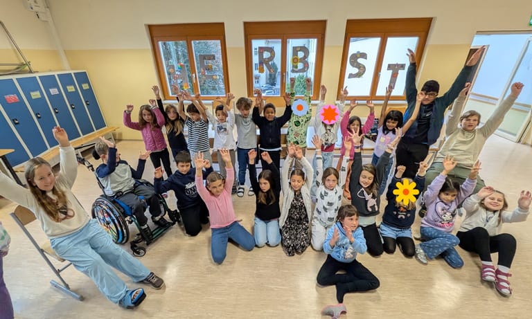 Eine Gruppe von Kinder streckt die Hände in die Luft.