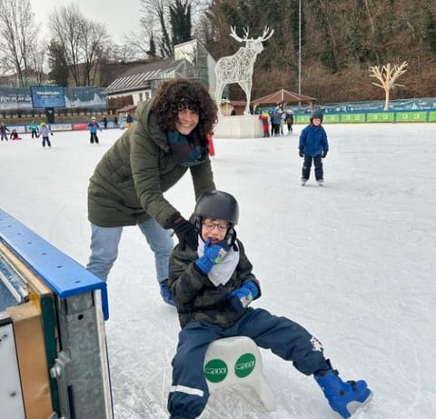 Lehrerin fährt mit Kind auf dem Eislaufplatz.