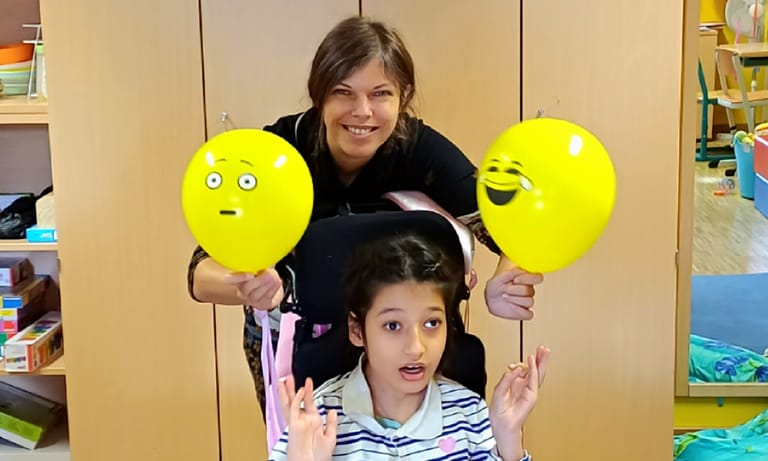 Kind hat zwei Luftballone - einen mit einem traurigen und einen mit einem fröhlichen Gesicht.