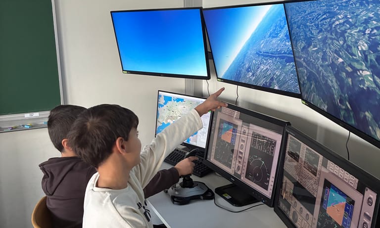 Zwei Kinder sitzen an einem Flugsimulator.