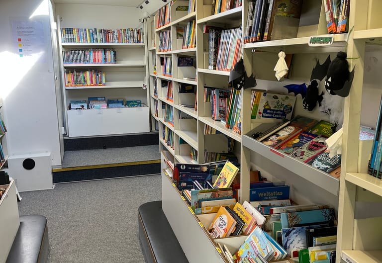 Kinderbücher stehen in Regalen im Bücherbus