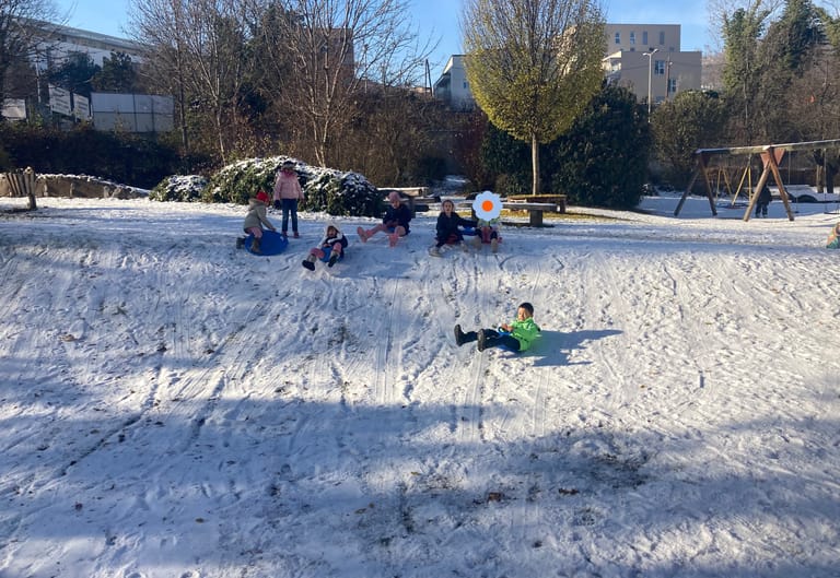 Kinder fahren mit Rodel den verschneiten Hügel hinab.