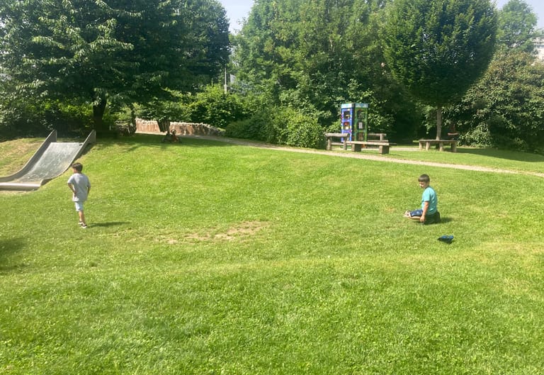 Kinder sitzen in der grünen Wiese.