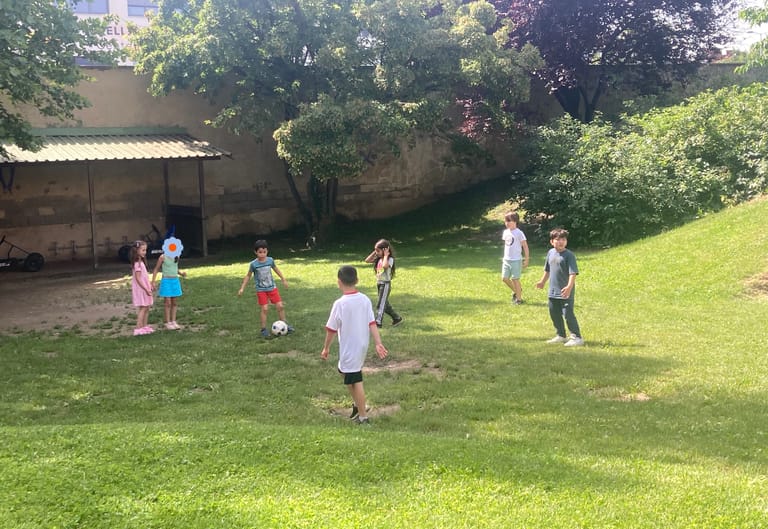 Kinder spielen auf grüner Wiese Fußball