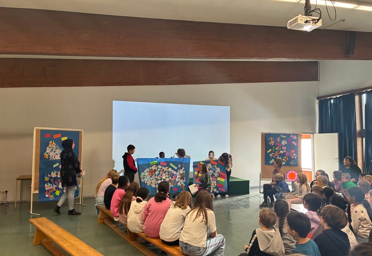 Viele Kinder hören eine Präsentation im Festsaal zu.