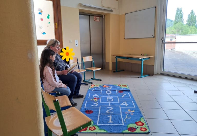 Frau liest zwei Kindern aus einem Buch vor.