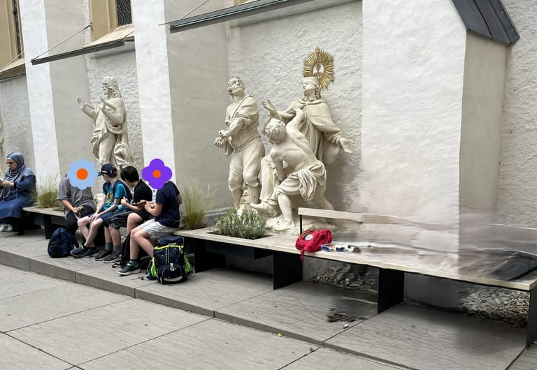 Personen sitzen vor Kirche und jausnen.