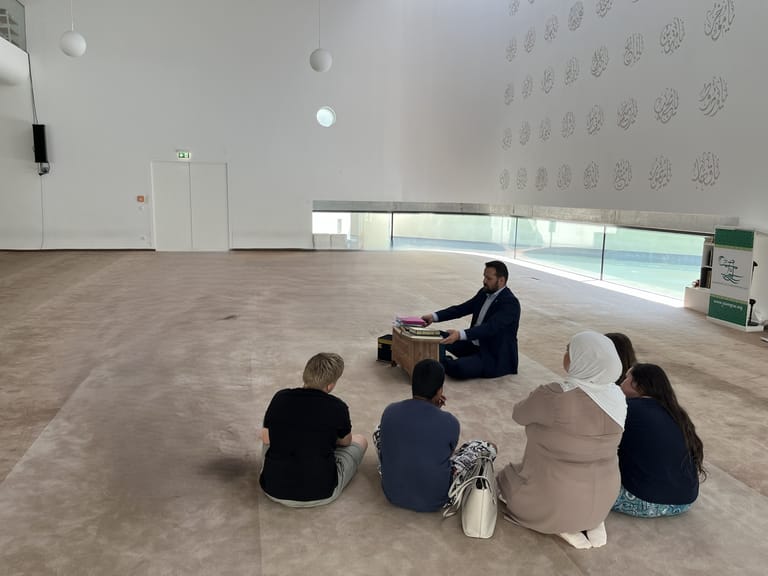 4 Kinder sitzen in einem hellen Raum in der Moschee.