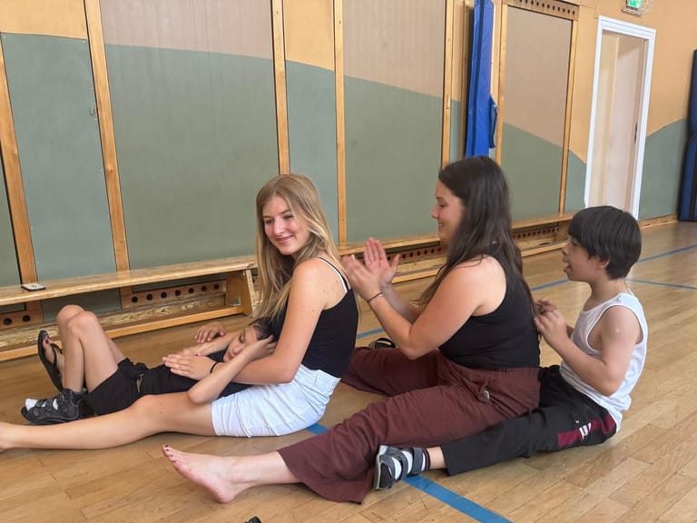 Vier Personen sitzen hintereinander und massieren sich den Rücken