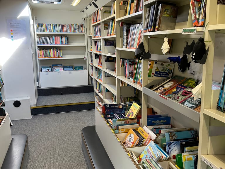 Kinderbücher stehen in Regalen im Bücherbus