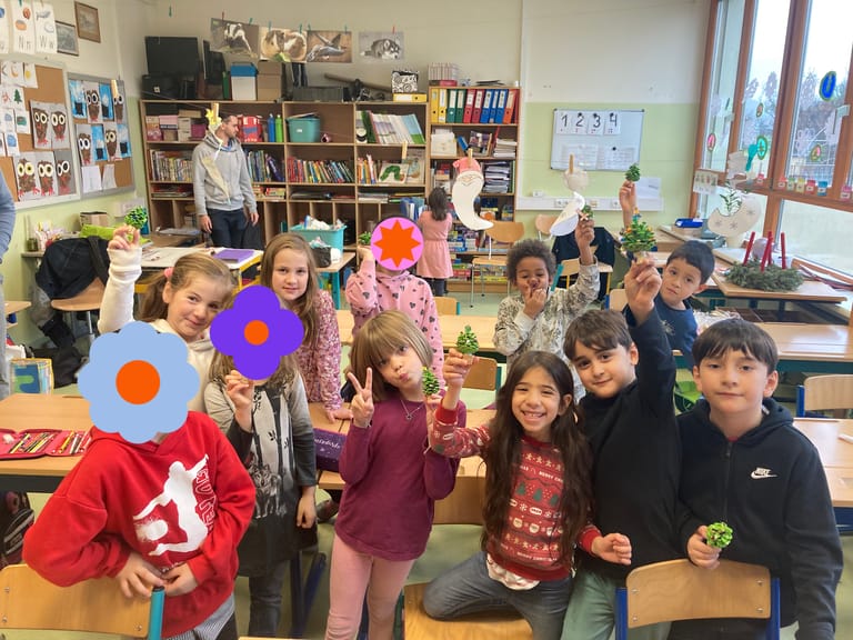 Kinder halten stolz ihre gebastelten Werke in die Luft.