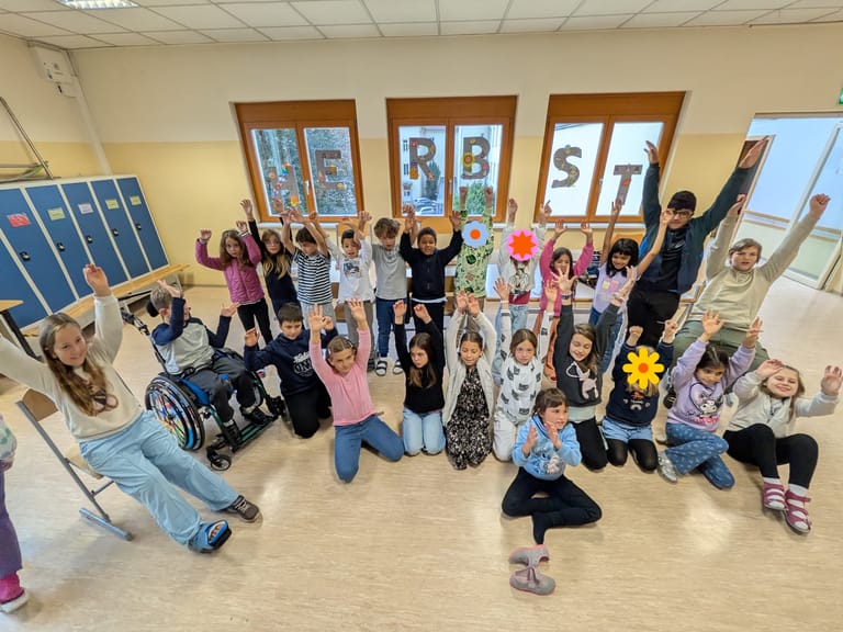 Eine Gruppe von Kinder streckt die Hände in die Luft.