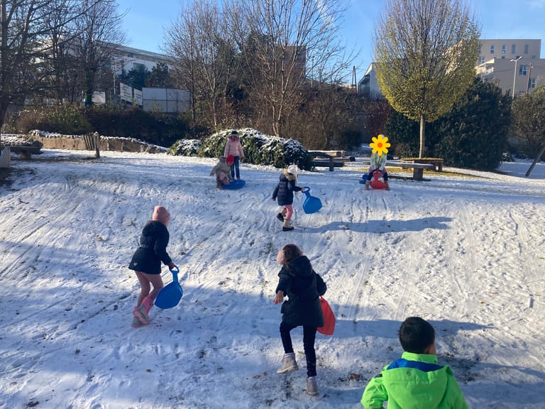 Kinder fahren mit den Bobs den Hügel hinunter.