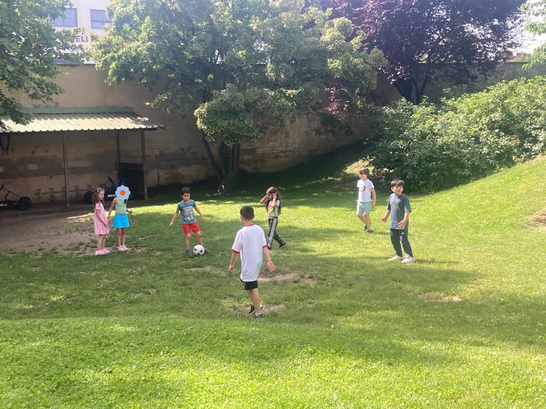 Kinder spielen auf grüner Wiese Fußball