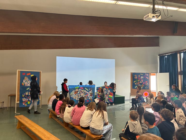 Viele Kinder hören eine Präsentation im Festsaal zu.