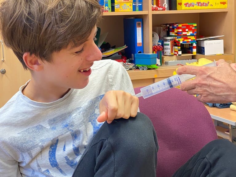 Kind bekommt beim Theater eine Spritze und lächelt.