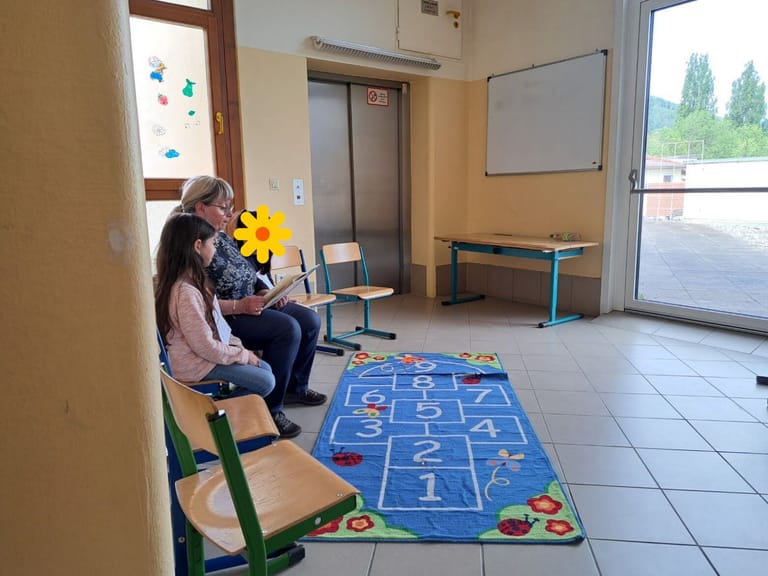 Frau liest zwei Kindern aus einem Buch vor.