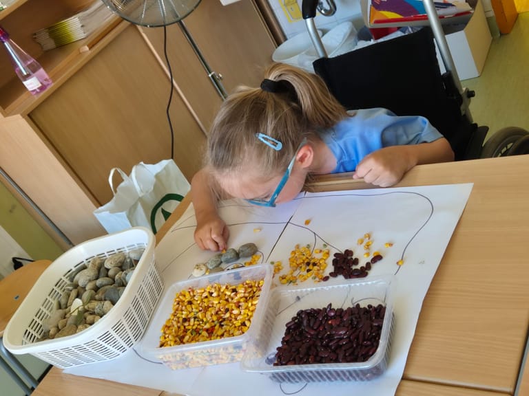 Kind legt mit Naturmaterialien ein Bild