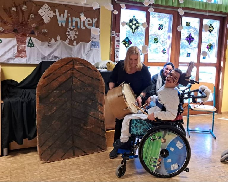 Kind im Rollstuhl spielt Trommel