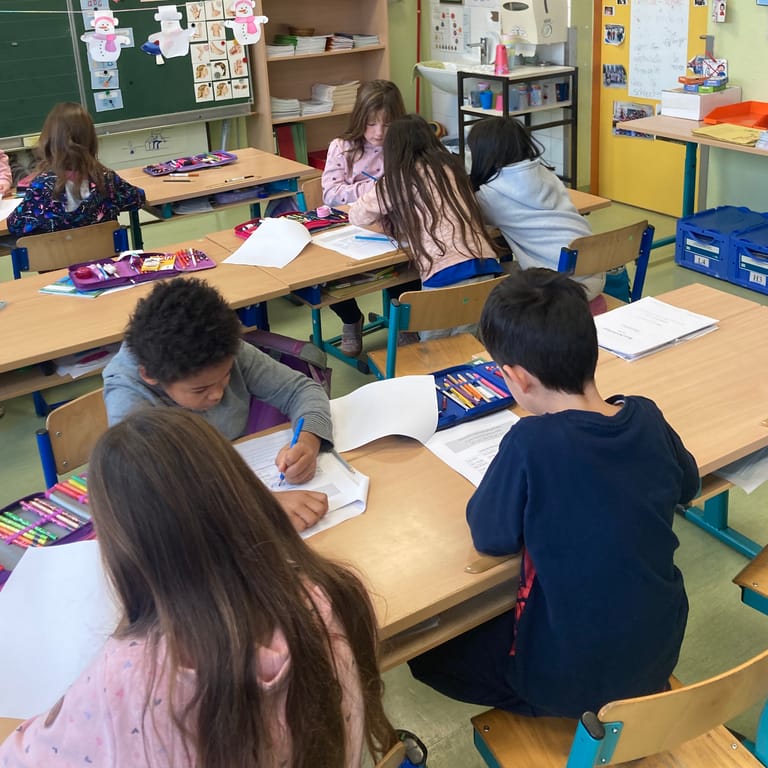 Kleine Gruppen von Schulkindern arbeiten gemeinsam an einem Arbeitsblatt.