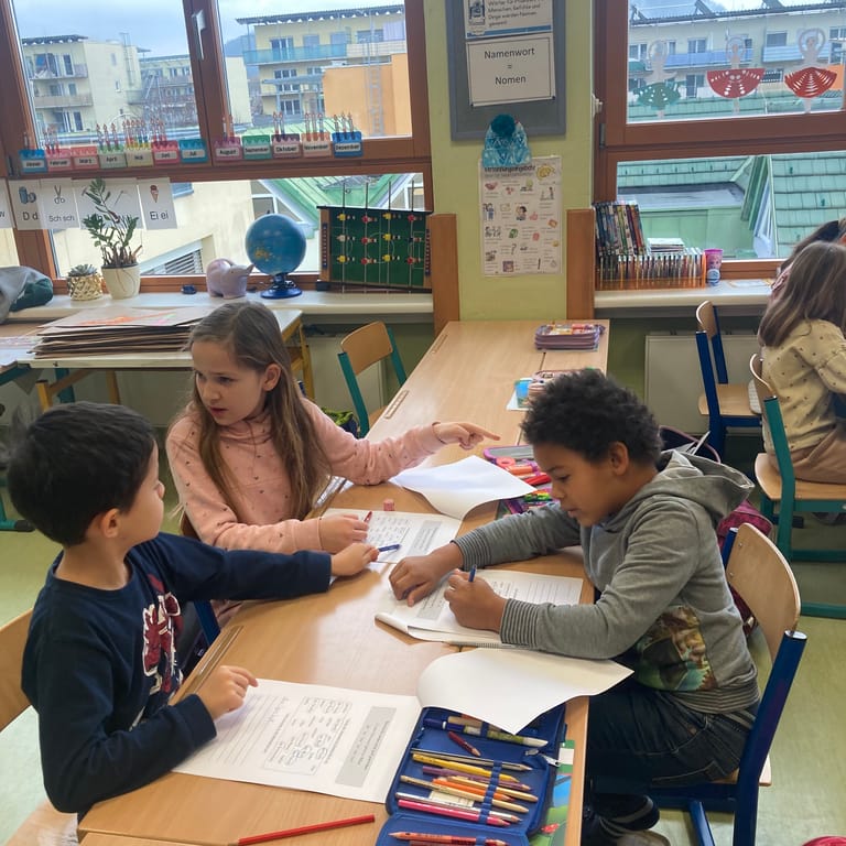 Kinder arbeiten an einem Arbeitsblatt zusammen.