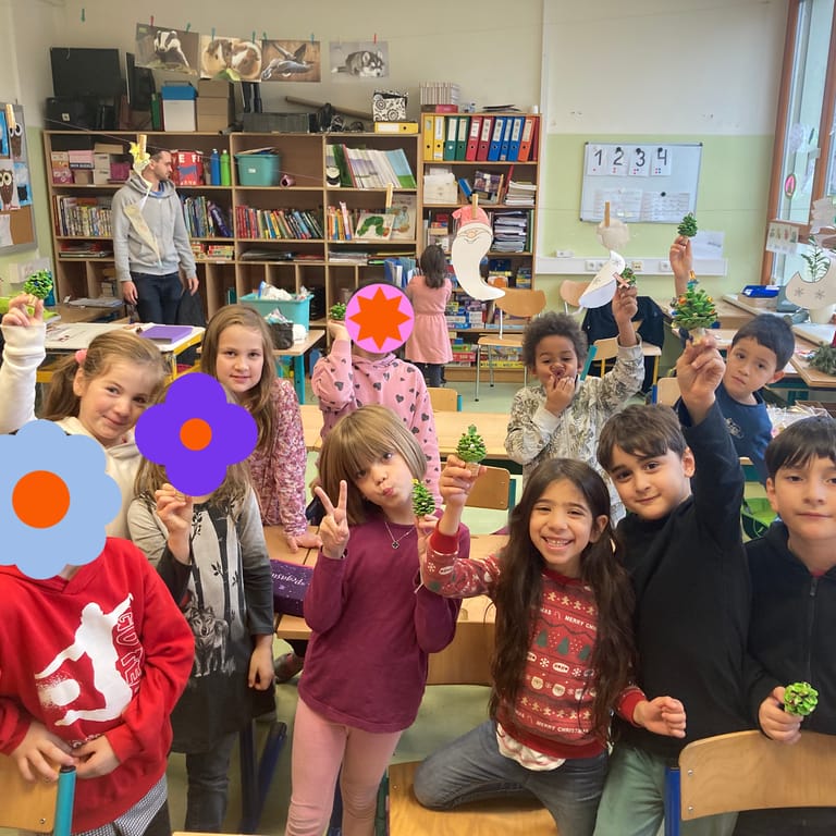 Kinder halten stolz ihre gebastelten Werke in die Luft.