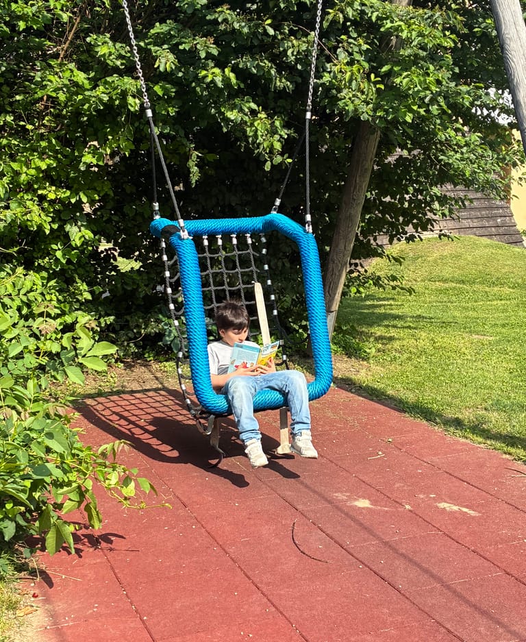 Kind liest in Korbschaukel