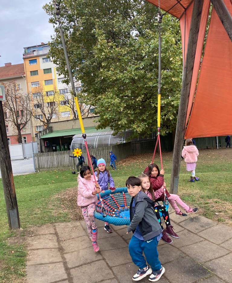 Kinder schaukeln in der Korbschaukel.